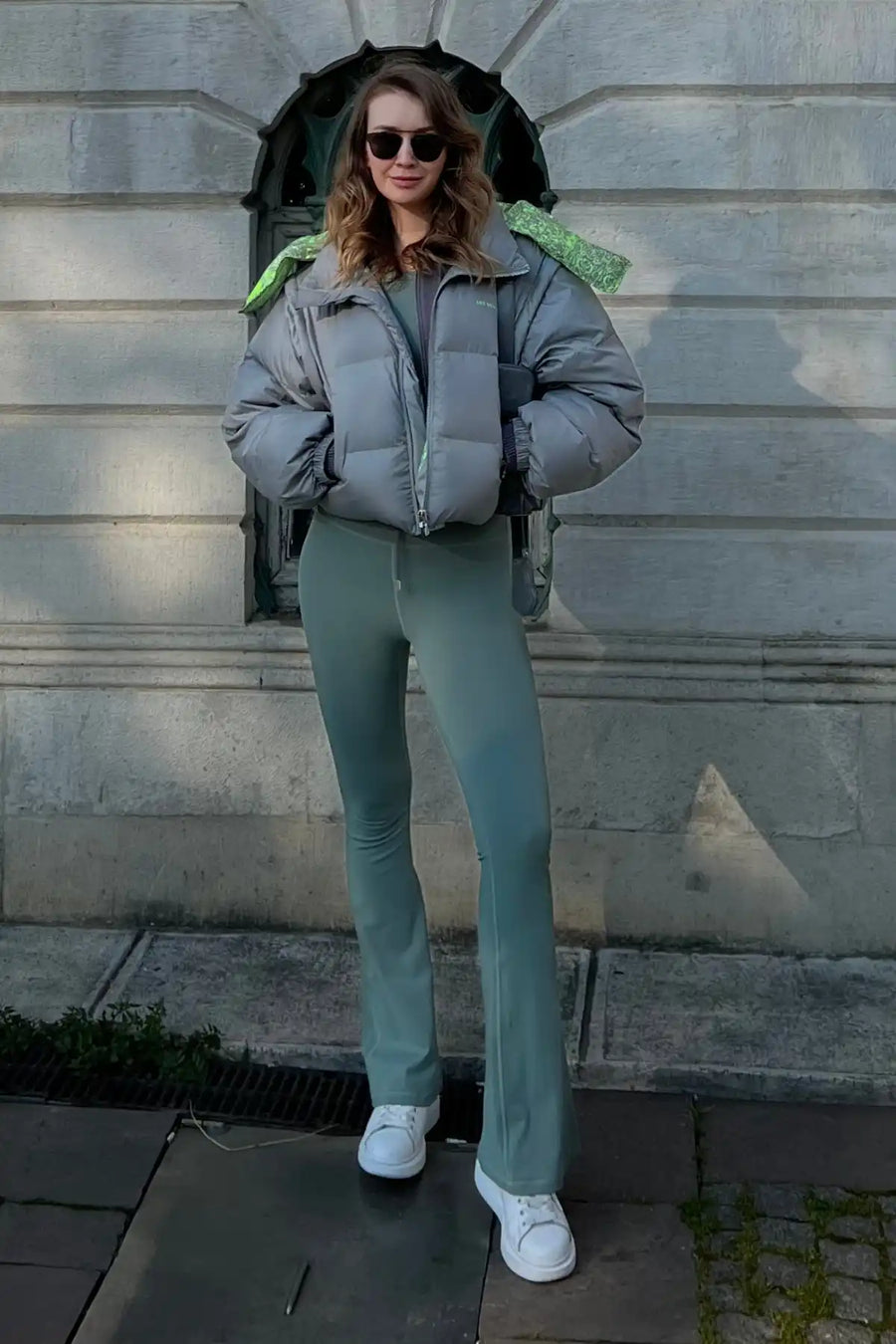 Gri şişme ceket ve yeşil pantolon giymiş kadın.